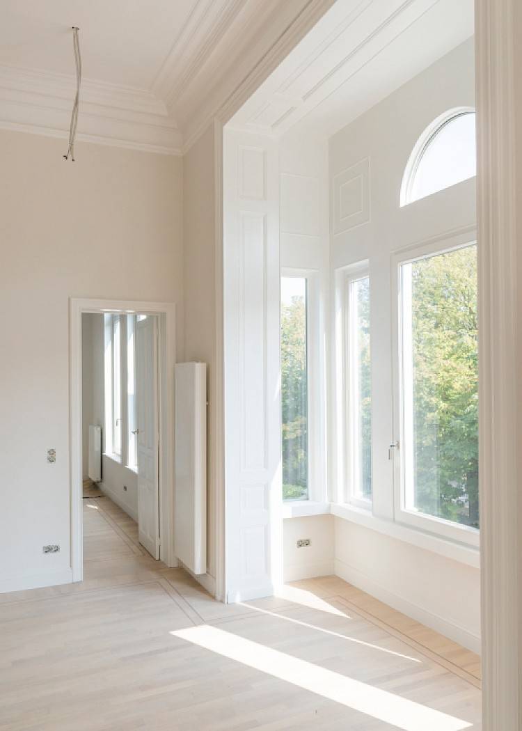 Gerenoveerde kamer met witte sierlijsten en een grote uitsprong met raam